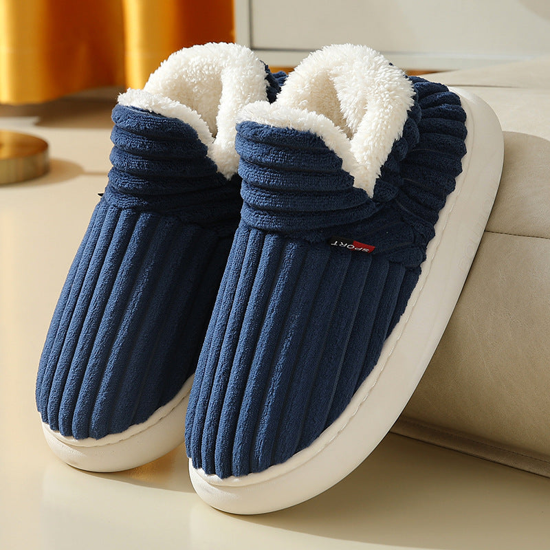 Navy blue plush indoor slippers with white fleece lining and ribbed texture on beige surface