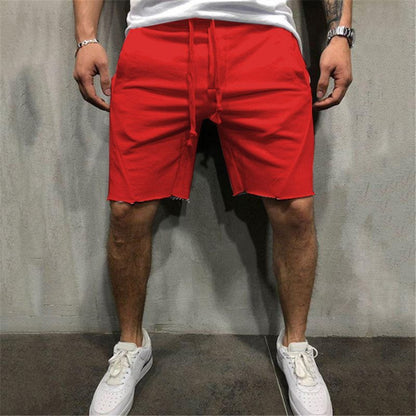 Man wearing bright red cotton gym shorts with raw hem and drawstring, paired with white sneakers
