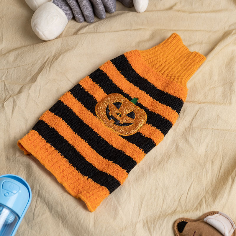 Cozy orange and black striped Halloween dog sweater with glittery jack-o'-lantern design on beige surface