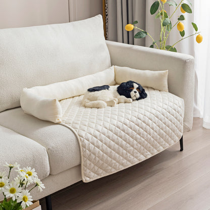Beige quilted pet mat with raised edges and black-white dog plush on white sofa in modern room