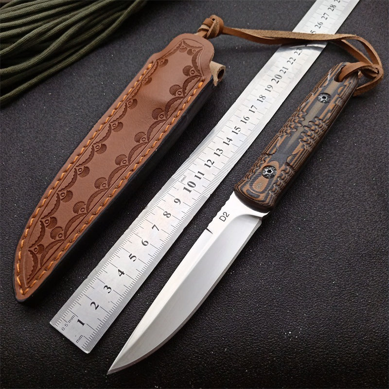 D2 steel folding survival knife with patterned G10 handle and brown leather sheath next to a ruler