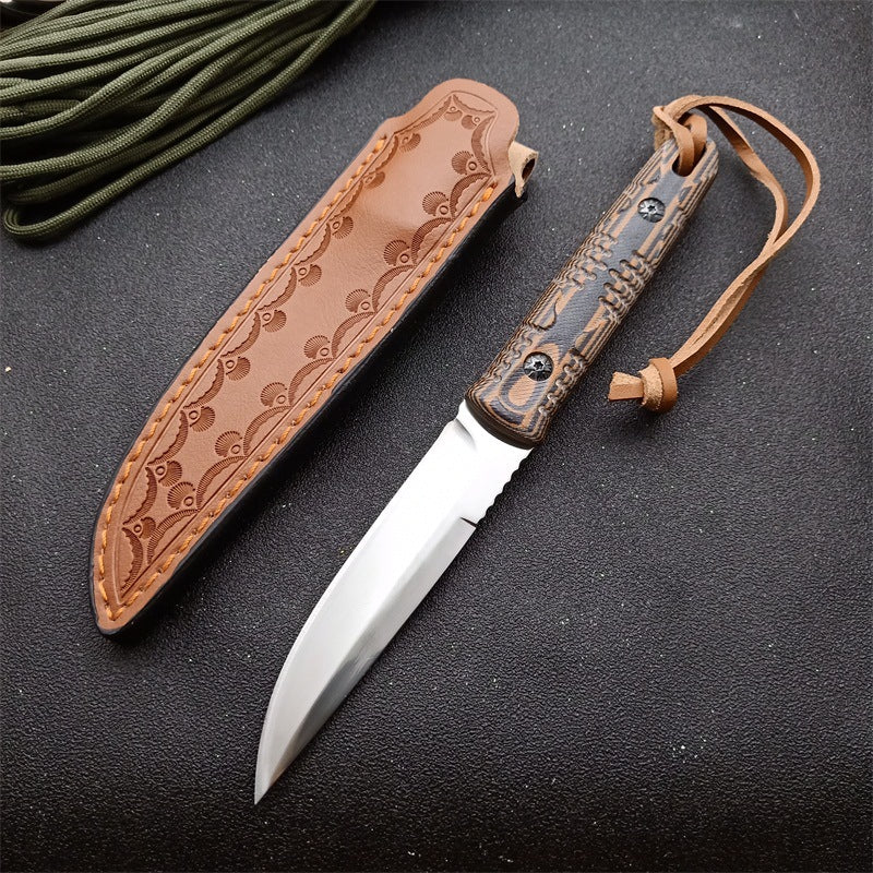 Fixed blade survival knife with wooden handle and leather sheath on dark textured surface