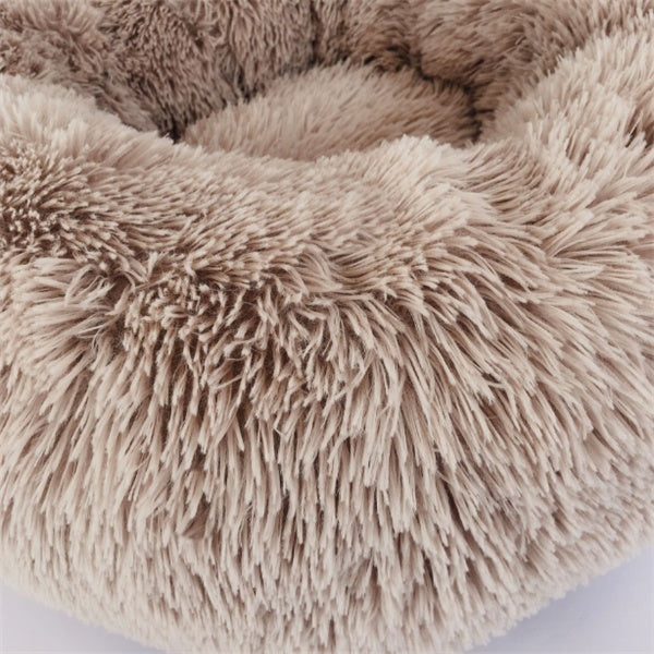 Close-up of a beige fluffy round plush pet bed with soft shaggy fabric, cozy for cats and dogs