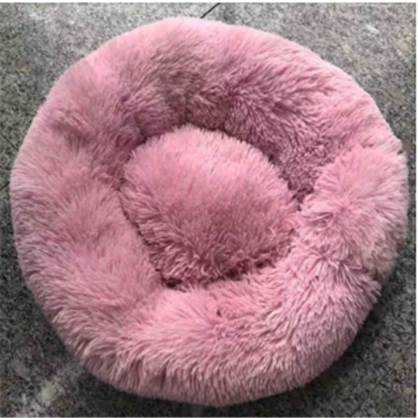 Round pink plush pet bed with soft fluffy cushion on gray carpet