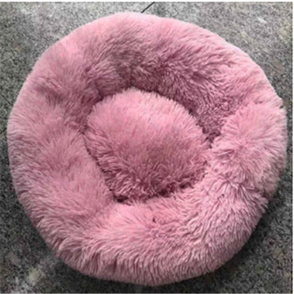 Round pink plush pet bed with soft fluffy cushion on gray carpet