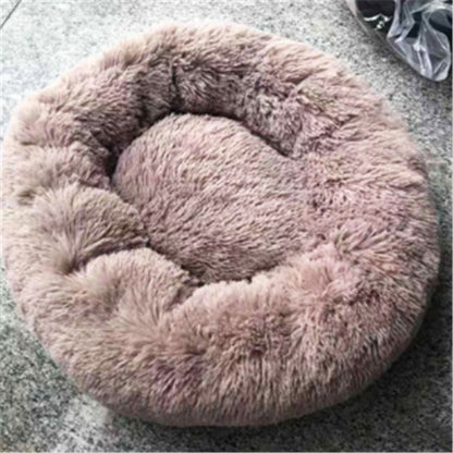 round plush pet bed in soft light brown with fluffy cozy texture on gray surface