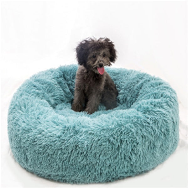 small black dog sitting on a round fluffy teal plush pet bed with a cozy nest design