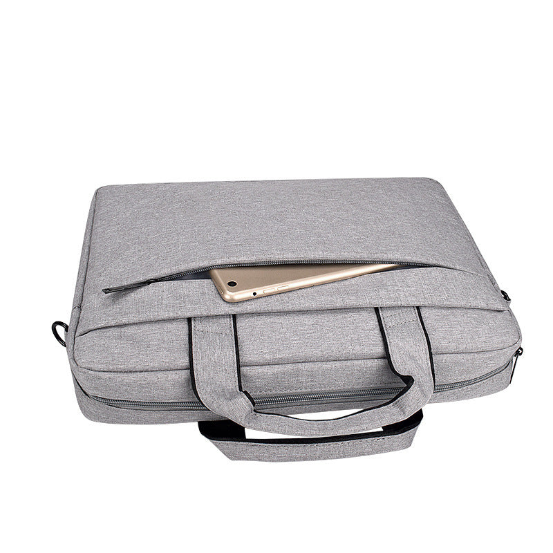 Gray fabric laptop bag with handles and front zipper pocket holding a gold tablet