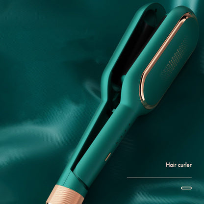 Teal electric hair curler with rose gold accents on matching teal fabric background