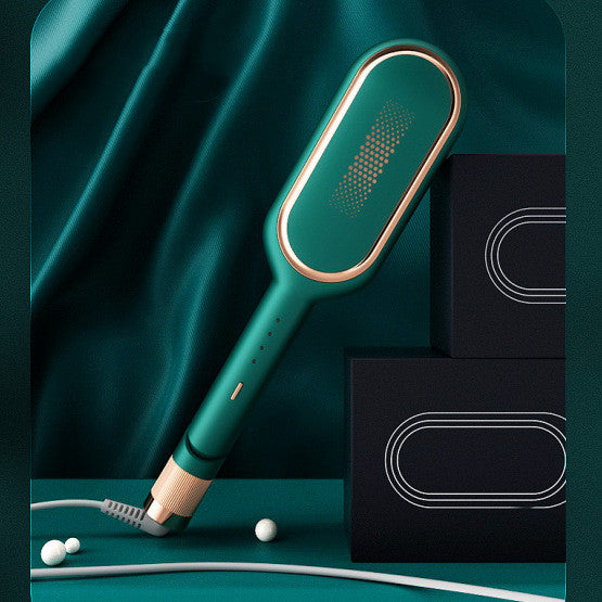 Green and gold electric hair straightening brush with digital display and power cord on dark green fabric background