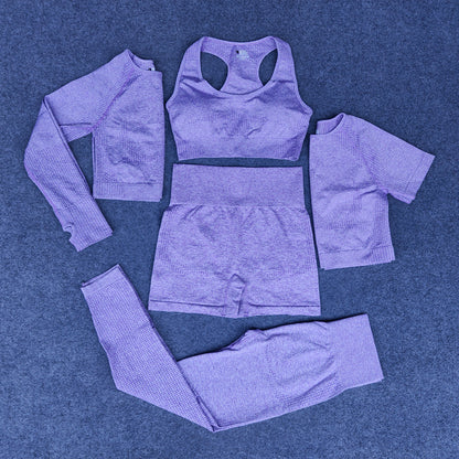 Purple seamless women's athleisure set including long-sleeve top, sports bra, shorts, leggings, and short-sleeve crop top on blue background