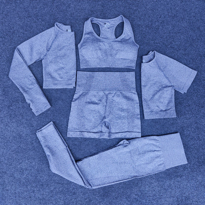 Five-piece blue seamless nylon athleisure set including sports bra, long-sleeve crop top, short-sleeve top, shorts, and leggings on carpet