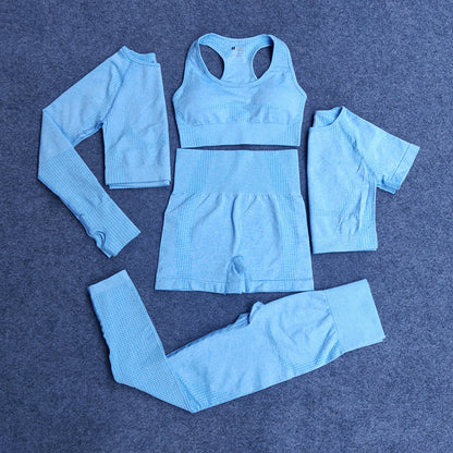 Light blue seamless five-piece activewear set including long sleeve crop top, sports bra, shorts, short sleeve top, and leggings on gray background
