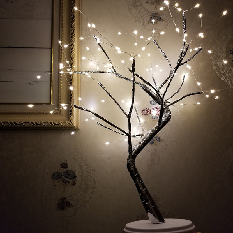 LED bonsai tree light with multiple small warm white lights on dark branches against vintage floral wallpaper