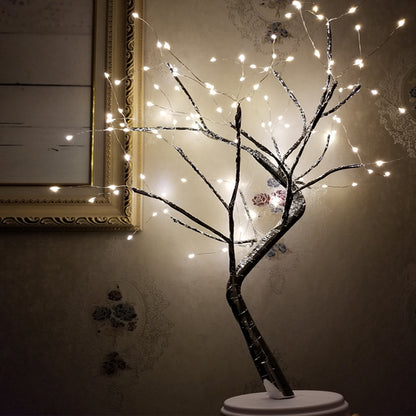 LED bonsai tree light with multiple small warm white lights on dark branches against vintage floral wallpaper