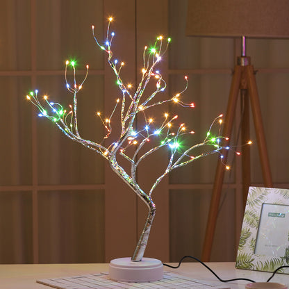 LED bonsai tree light with multicolor star-shaped lights on white base in cozy room setting