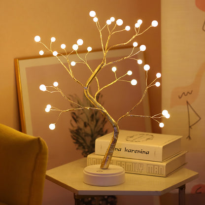 Pink pearl LED bonsai tree night light glowing on table with books and warm decor