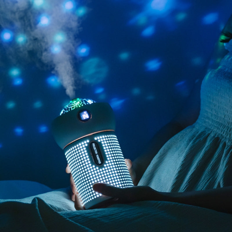 Person holding glowing USB humidifier with star projector in a dark room