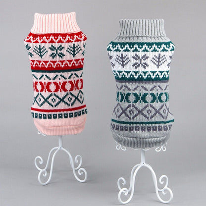 Two cozy knit pet sweaters on white metal stands, one pink with red and green patterns, one gray with green and purple designs