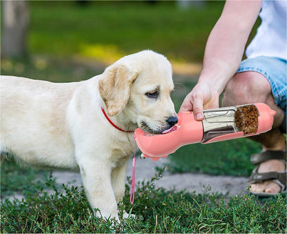 Yellow Labrador puppy drinking water from a pink 3-in-1 portable pet water bottle with food dispenser outdoors