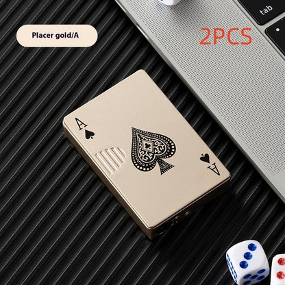 Gold zinc alloy lighter shaped like ace of spades poker card on black textured surface near laptop and dice