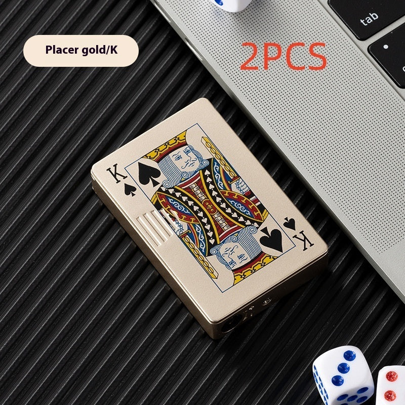 Gold zinc alloy lighter designed like King of Spades playing card on black surface with dice and laptop