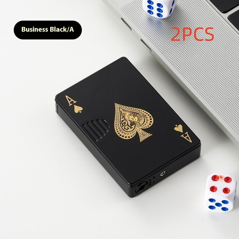 Black poker card-shaped zinc alloy lighter with gold Ace of Spades design beside laptop and dice