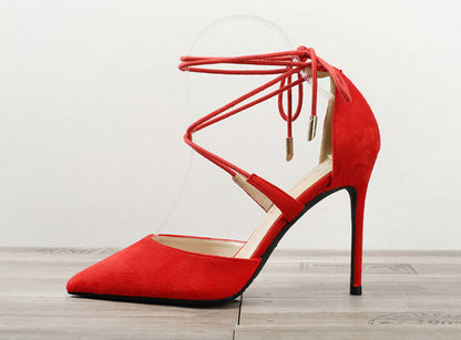 Red women's pointed toe high heel sandal with ankle wrap straps on wooden floor