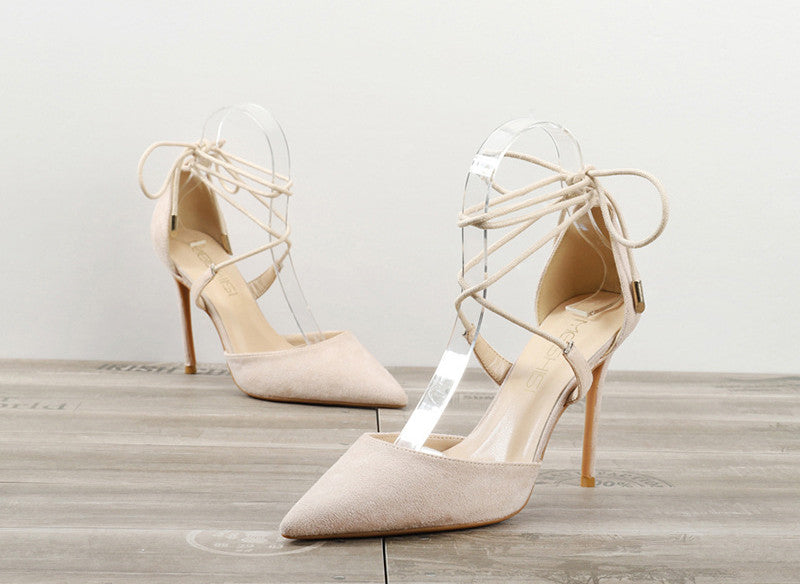 Beige women's pointed-toe high heel sandals with ankle wrap laces on wooden floor
