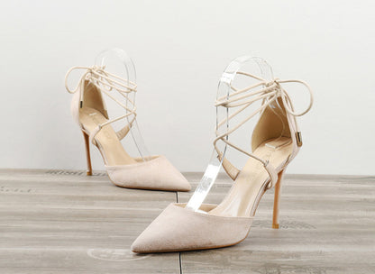 Beige women's pointed-toe high heel sandals with ankle wrap laces on wooden floor