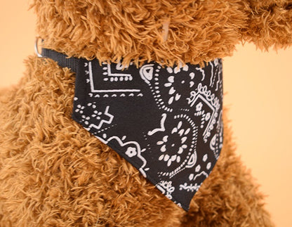 Curly brown dog wearing black and white patterned adjustable pet bandana on beige background