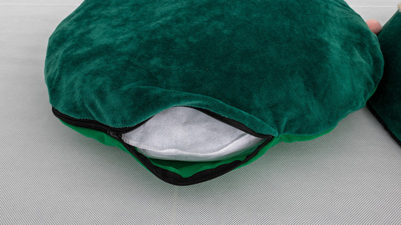 Close-up of green velvet zippered pet bed with white cushion inside on gray surface