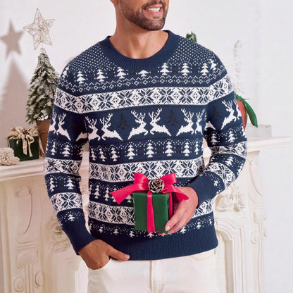 Man wearing blue and white Christmas sweater with reindeer and tree patterns holding green gift box with red ribbon