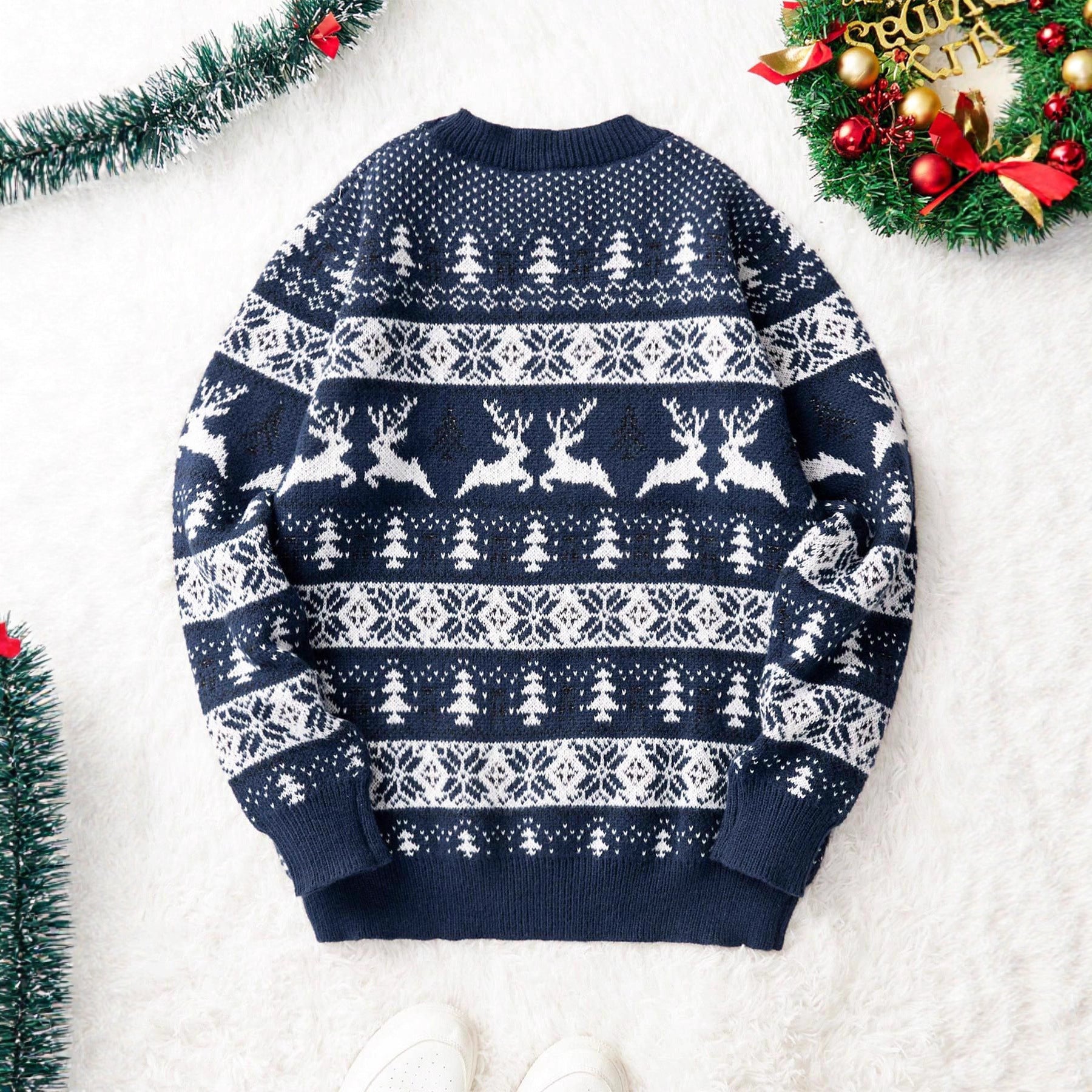 Navy blue Christmas sweater with white reindeer and tree patterns on white fuzzy background