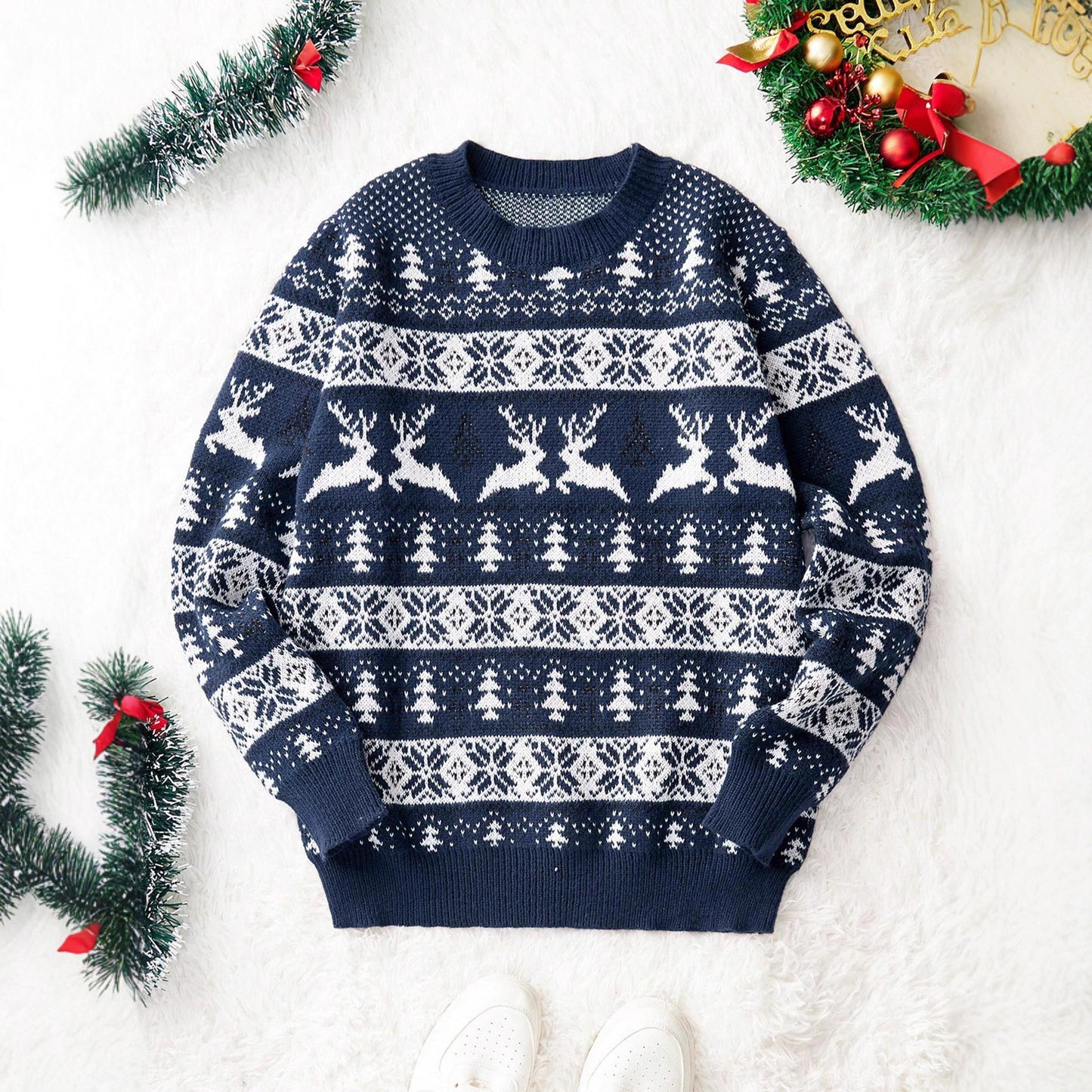 Navy blue Christmas sweater with white reindeer, snowflakes, and tree patterns on white background