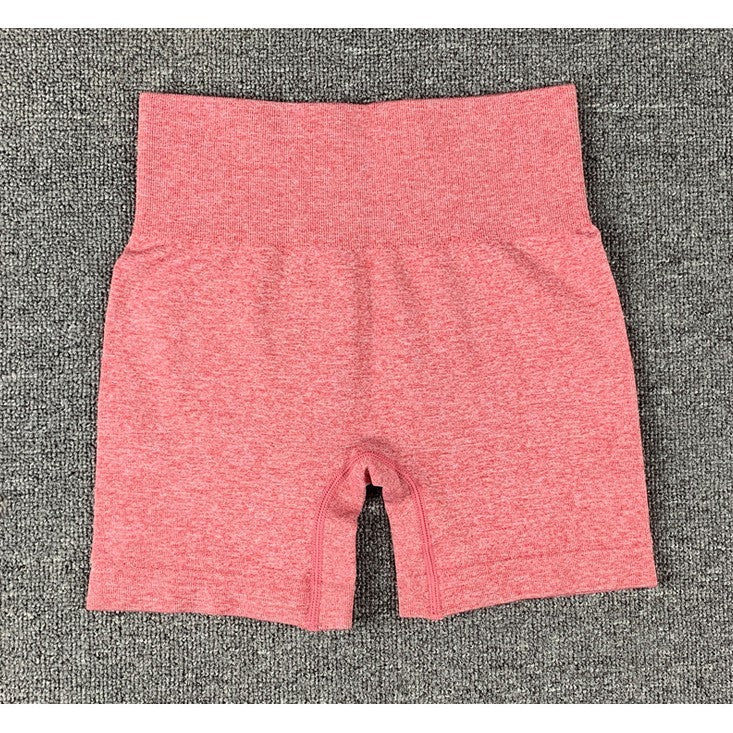 Red women's seamless high-waist yoga shorts laid flat on gray textured surface