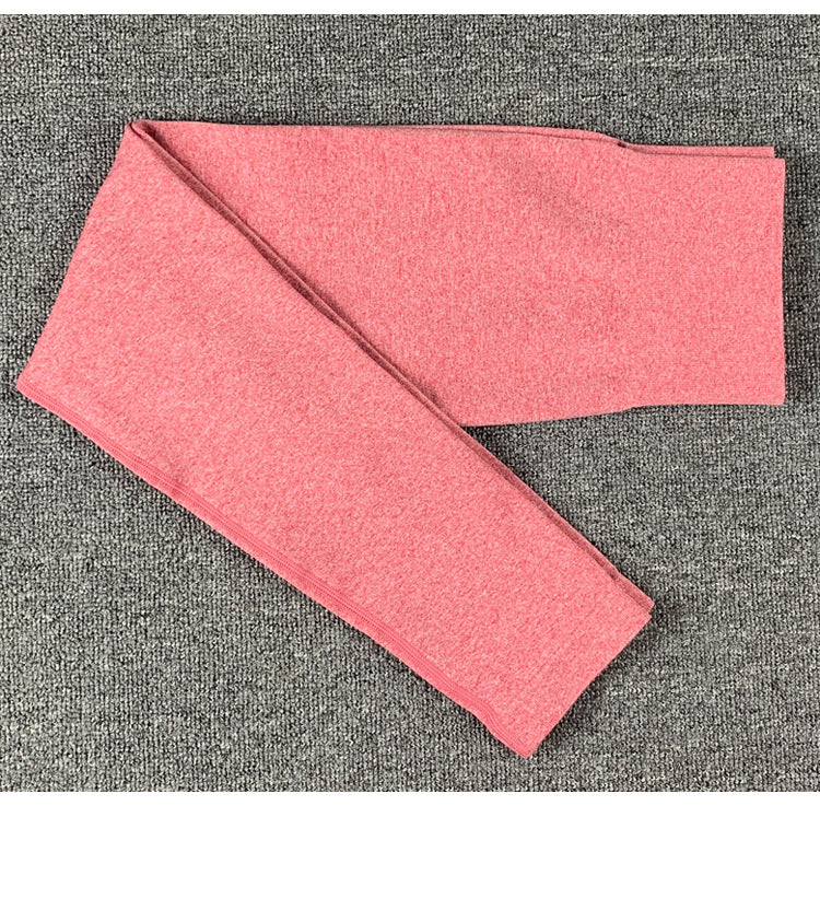 Folded pink women's yoga pants on gray carpet, soft activewear leggings for workouts