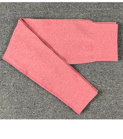 Folded pink women's yoga pants on gray carpet, soft activewear leggings for workouts