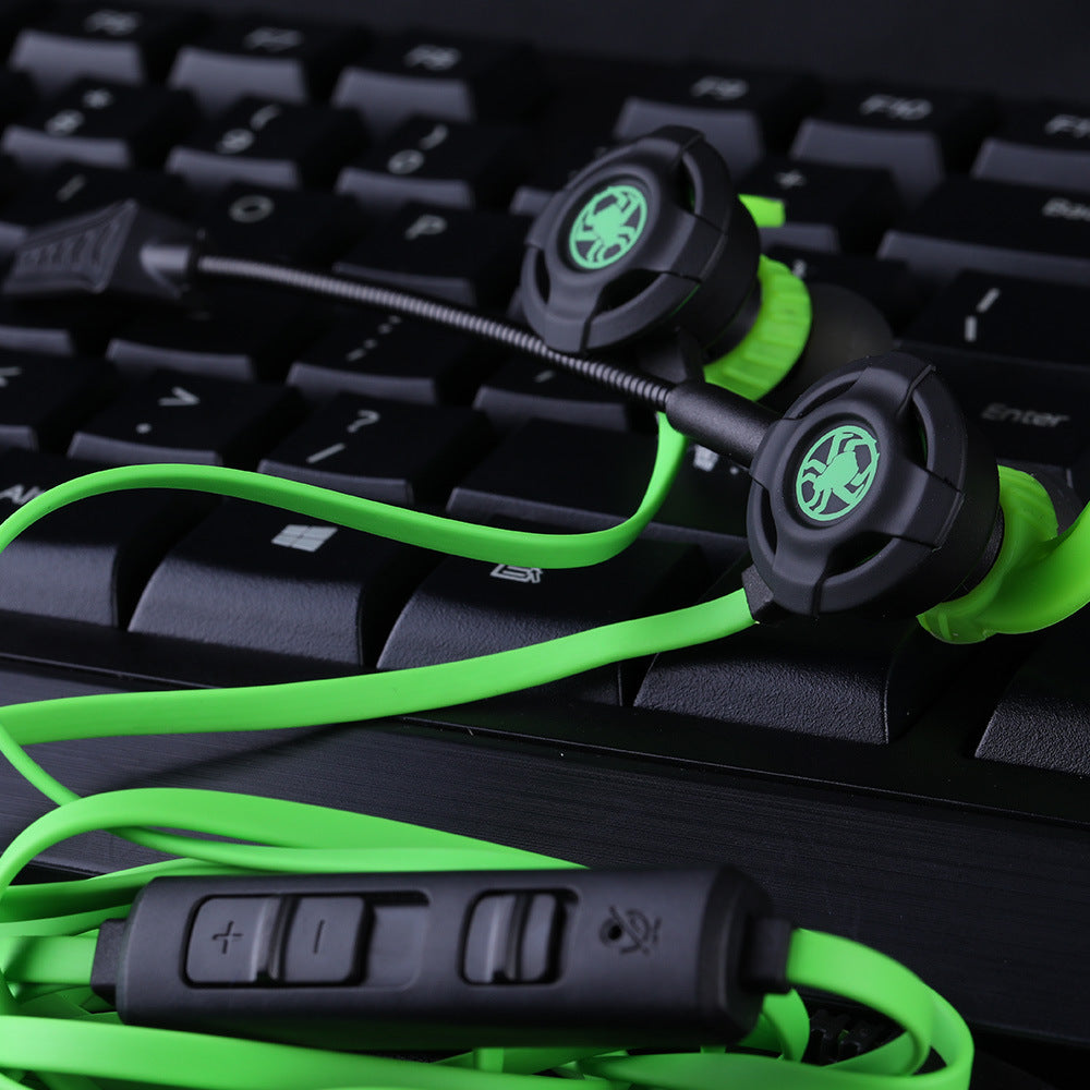 Black and green wired in-ear gaming headset with microphone and volume control on black keyboard