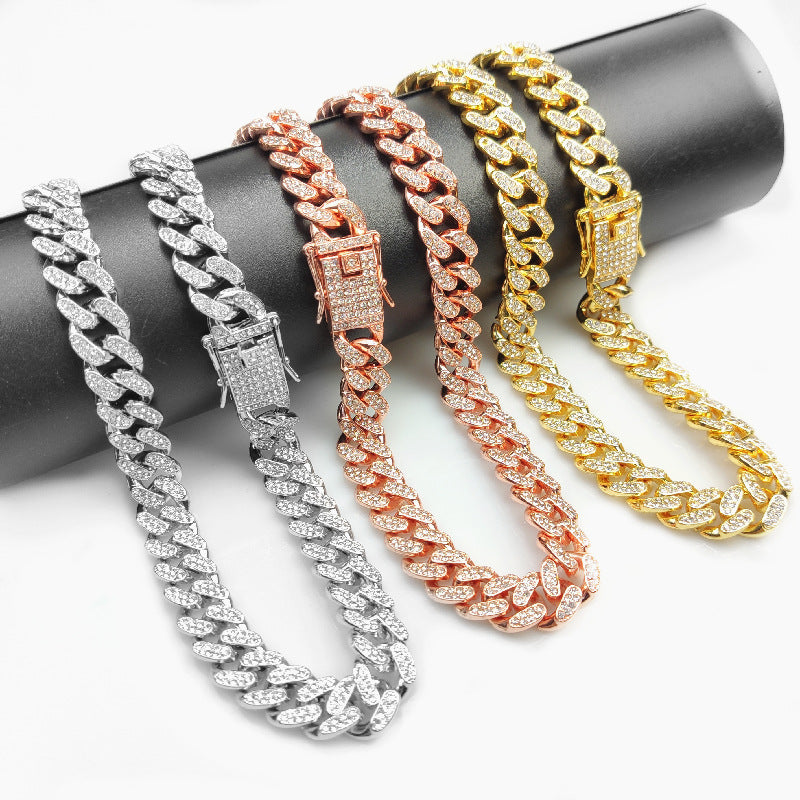 Three hip hop style Cuban link chains in silver, rose gold, and gold with diamond-like accents displayed on black rod