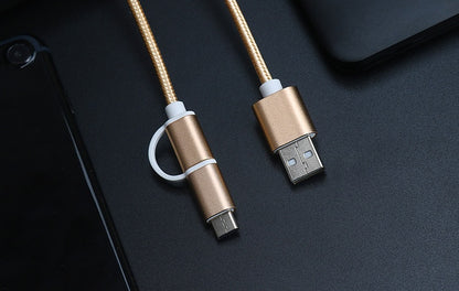 Rose gold braided 2-in-1 USB-C and micro USB fast charger cable on black surface with part of a smartphone and laptop
