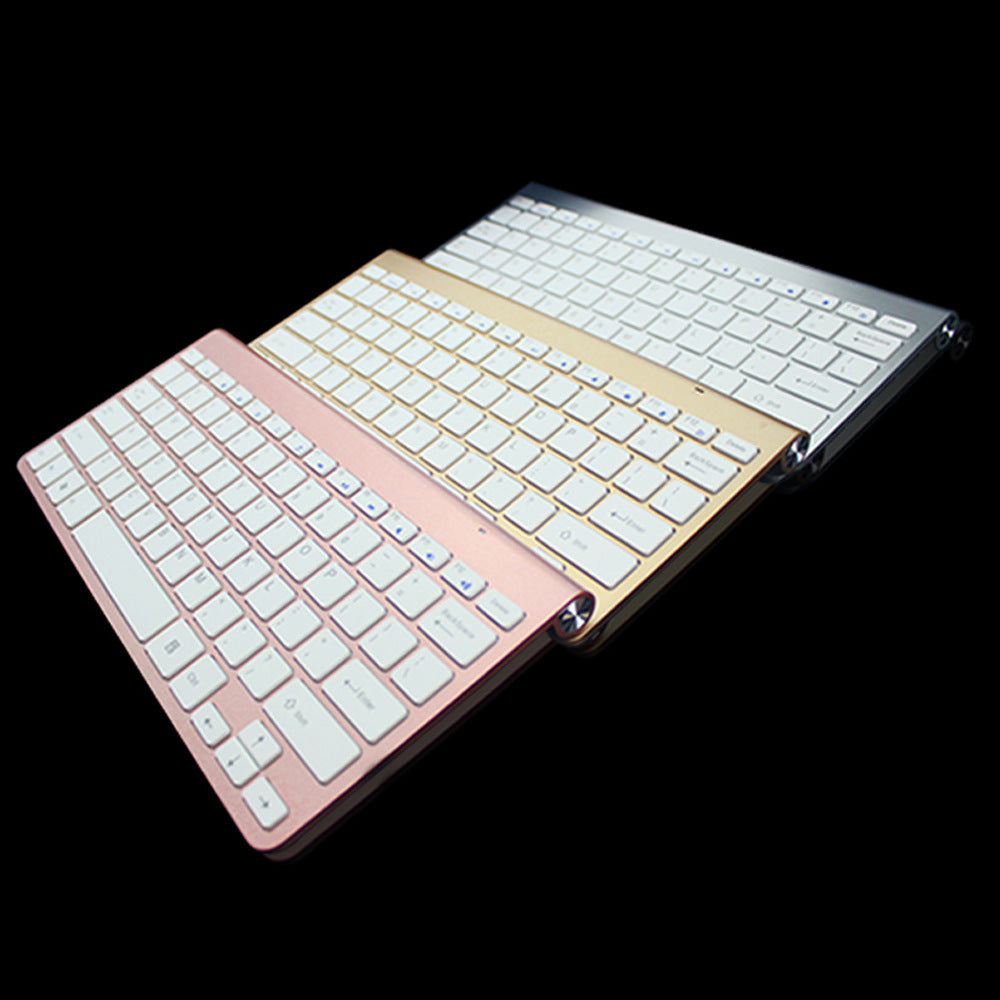 Three slim wireless keyboards in rose gold, gold, and silver colors on black background