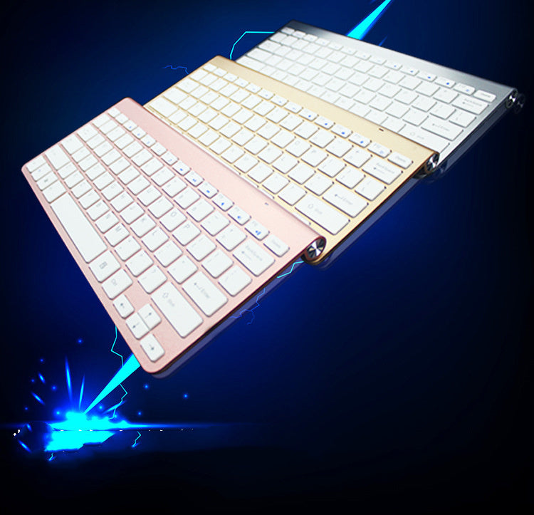Three compact wireless keyboards in rose gold, gold, and silver on a dark background with blue light effect