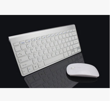 White compact wireless keyboard and matching white wireless mouse on black reflective surface