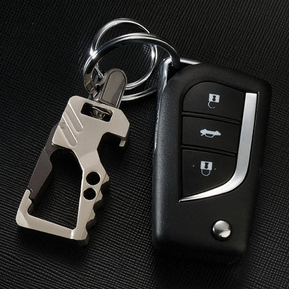 Men's leather car key chain pendant with a sandy gold multi-tool and black car remote on black textured surface