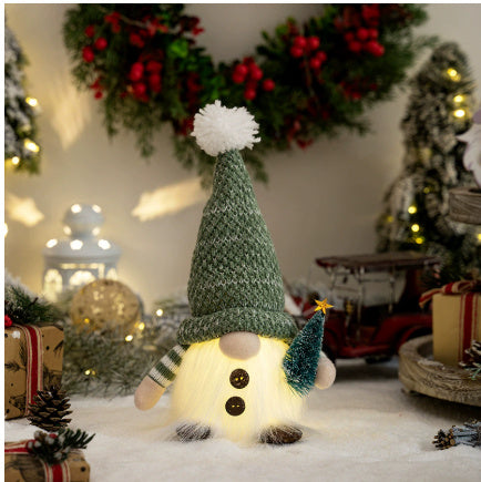 Christmas gnome decoration with green knit hat and miniature tree, surrounded by festive wreath and lights