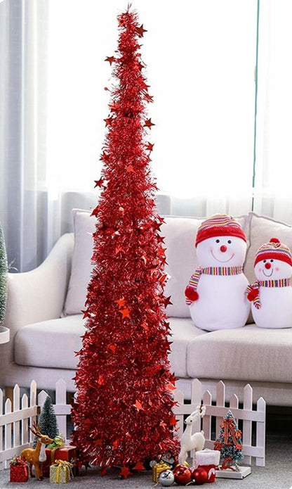 Tall slim red tinsel Christmas tree with star decorations surrounded by ornaments and plush snowmen on a white sofa