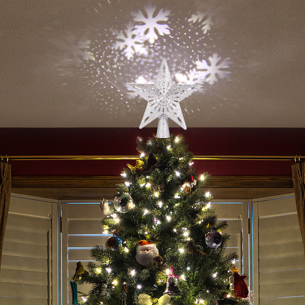 Decorated Christmas tree with white star topper projecting snowflake light patterns on the ceiling