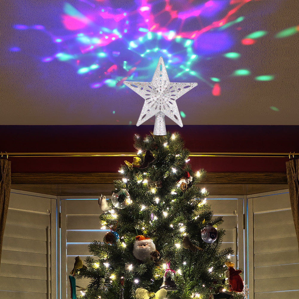 Christmas tree with white lights and glittery star topper projecting colorful star and snowflake patterns on ceiling