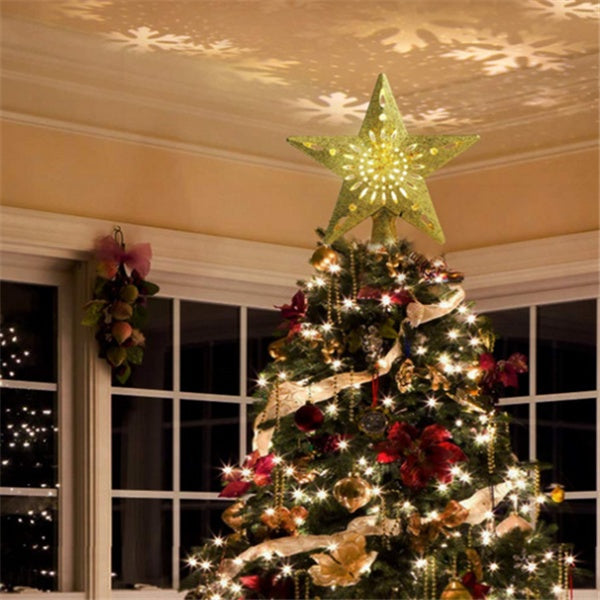 Decorated Christmas tree with glowing star topper projecting snowflake lights on ceiling